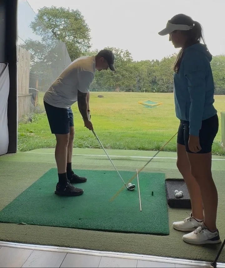 Jae watching a student hit balls on the range